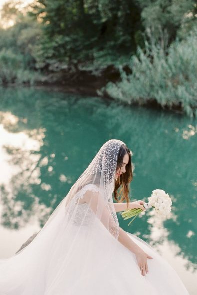 Bride with tulle romantic dress with a beaded veil in the lakeside,
