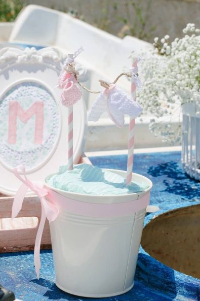 Laundry inspired party decoration with mini white and pink crochet dresses and flower arrangements with white baby's breath flowers.