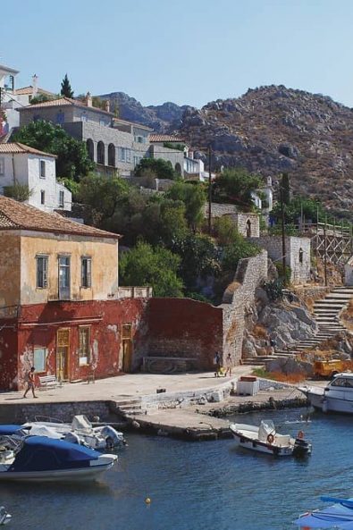 Island dock village in the summertime with white houses, stone buildings and little boats floating in the sea.