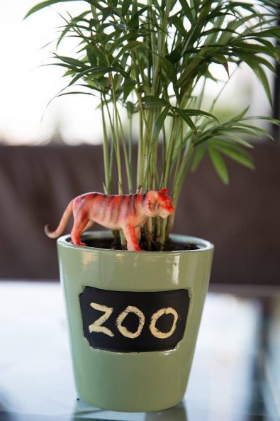 Plant pot with plastic tiger decoration.