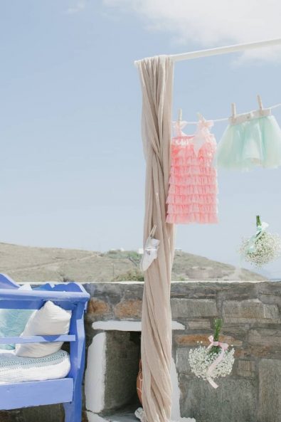 Baby laundry inspired party backdrop with hanging girl's clothes and white flower bouquets.