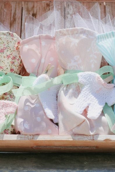 Baby laundry inspired christening ideas favors for a baby girl with fabric bags in pastel colored fabric, crochet baby clothes, and mint ribbons.