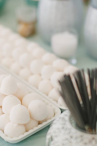 White fondant sweets in white trays for a wedding candy bar.