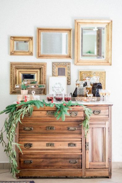 Christmas decoration with pine and eucalyptus on a vintage bar cabinet with golden mirrors on the wall for a private Christmas dinner.