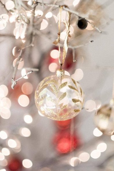 A delicate glass Christmas tree ornament with gold leaves and glitter for a private Christmas dinner.