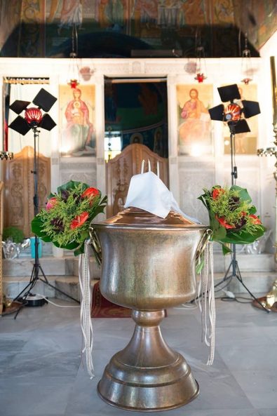 Bronze baptistery decorated with red flowers and green leaves for a boy baptism in Lycabettus hill.