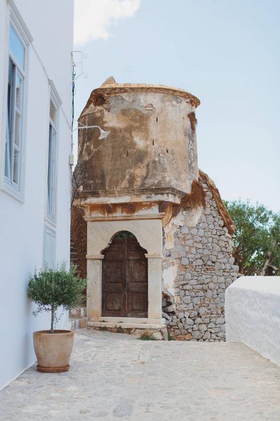 Big old wooden door of a stone chapel on a Greek island.