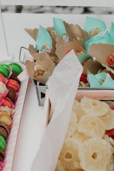 Sweets treats for a baptism party, chocolate, vanilla and pistachio macarons, dried pineapple, papaya, figs and paper cones filled with dried fruit.