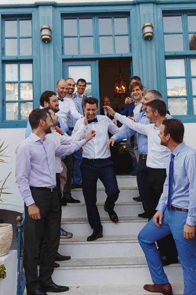 The groom squad and smiling groomsmen in navy blue suites teasing the groom before the wedding.