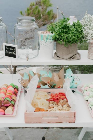 Candy bar christening ideas with homemade lemonade and cucumber flavored water, colorful macarons and meringues and paper party cones for sweets and dried fruit.