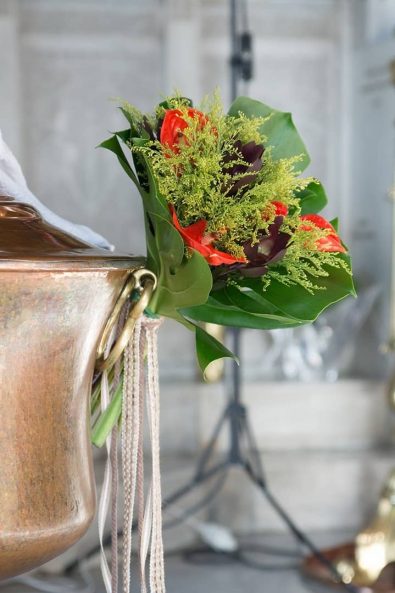 Baptistery flower decoration with red calla lilies, eucalyptus and banana leaves.