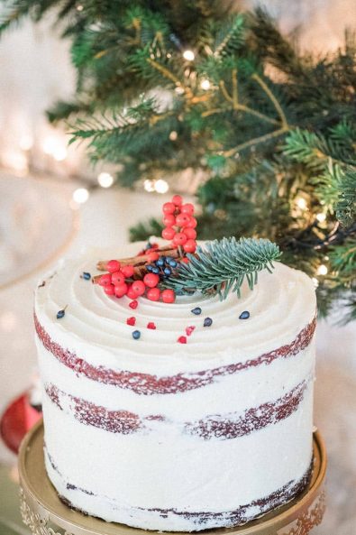 Christmas red velvet wedding cake with red berries and pine for a private Christmas dinner.