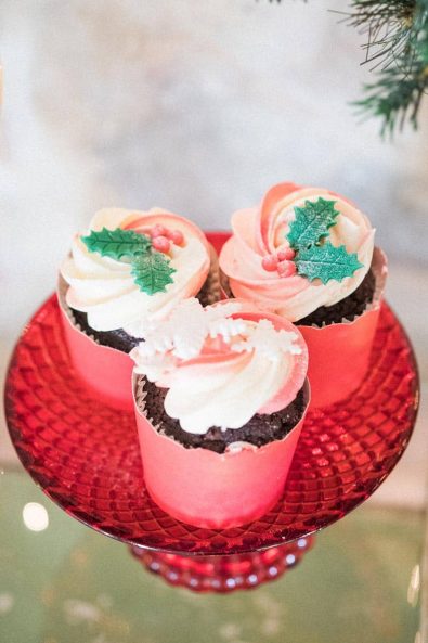 Festive chocolate cupcakes in a red paper case and candy cane buttercream with decorative snowflakes and mistletoe.