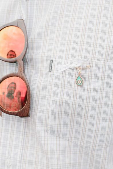 Close up shot of man's shirt with christening pin martiriko with gold and teal evil eye pendant for baptism in Greece.