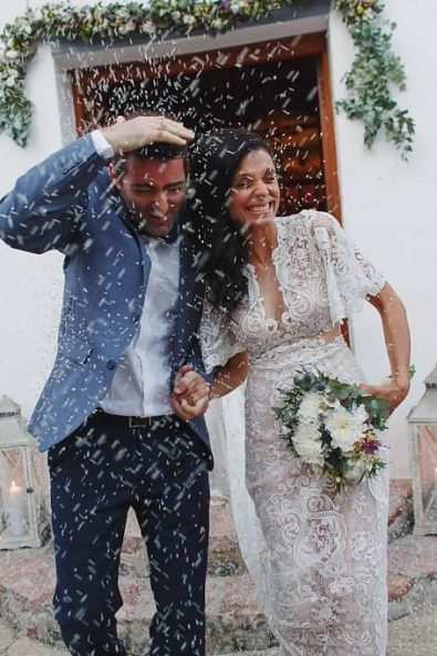 Bride and groom leaving the church while guests throw rice at them.