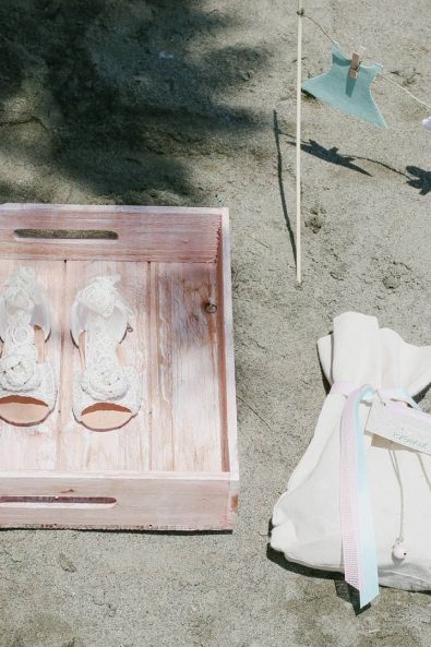 christening ideas - Detail shot of baptism girl shoes, celebration favor and laundry inspired decoration on the sand.