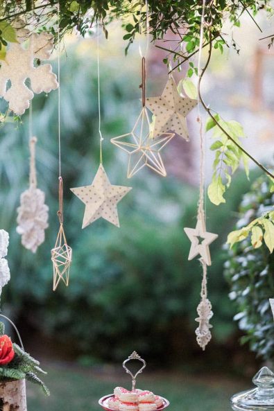 Hanging Christmas decoration with paper, metal, and wooden star ornaments.