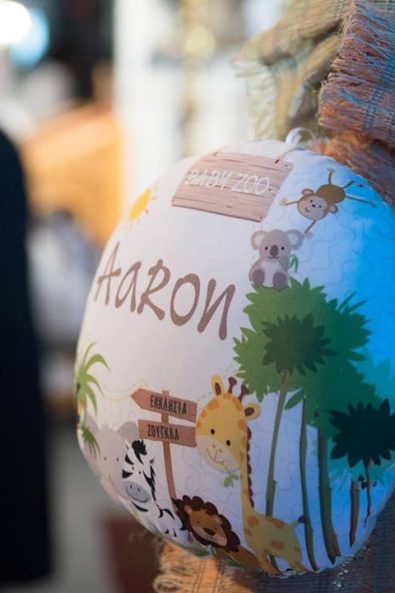 Detail shot of lampada candle with a decorative pillow with an elephant, a zebra, a lion, a giraffe, a koala bear, and a monkey for a boy baptism.