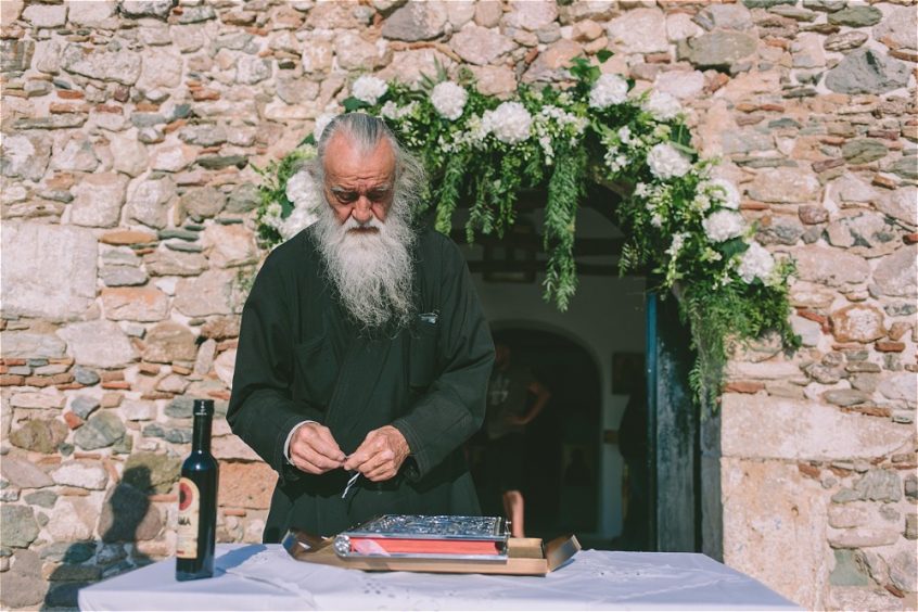 Priest in front of a Greek stone church