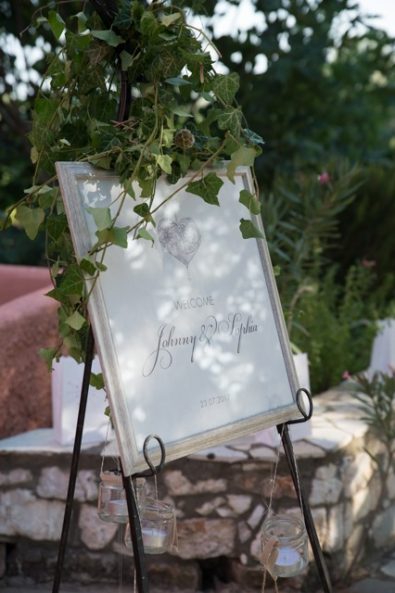 Vine wrapped welcome wedding sign with hanging candle holders.