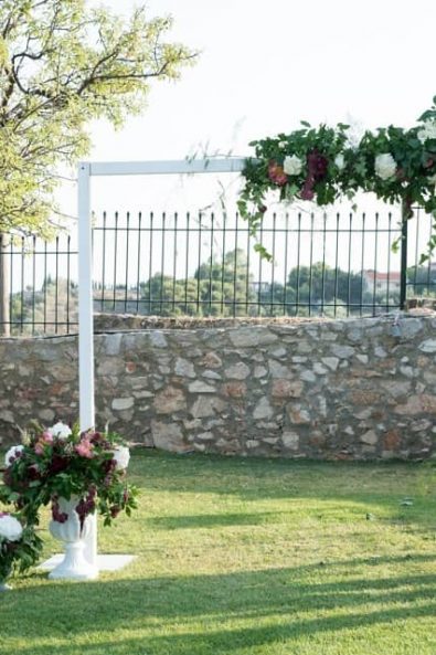 Beautiful organic floral decorated wedding arch with moody flowers and vine.