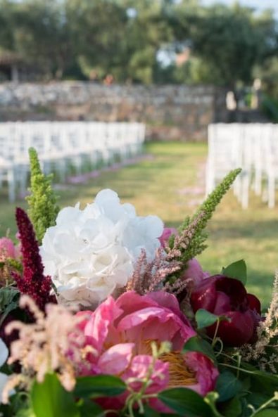 Colorful spring wedding floral arrangement with white hydrangeas, dark red and pink peonies, amaranthus and greenery for a Greek-Arabic wedding in Greece .