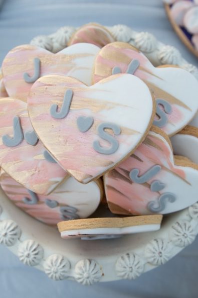 Stacked heart-shaped sugar cookies with peach and gold sugar paste and grey initials for a Greek-Arabic wedding in Greece.