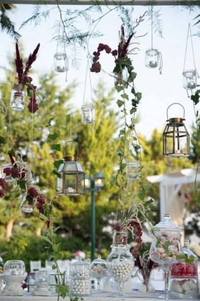 Ethereal hanging decoration with flowers and greenery, candle holders and wedding sweets at a Greek-Arabic wedding in Greece.