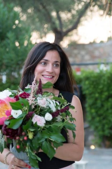 Katerina Strimmenou White stories wedding planner holding a wedding flower arrangement with peonies and roses at a Greek-Arabic wedding in Greece.