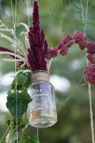 Hanging mason jar flower wedding decoration with amaranthus and vine.