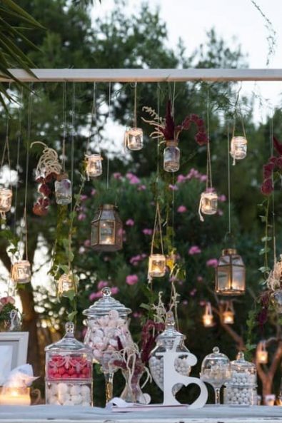 Floating lanterns and candles romantic wedding decoration and a candy bar with sweet treats and flowers.