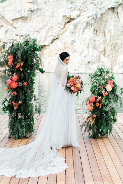 Bride with wedding veil holding bouquet at aisle