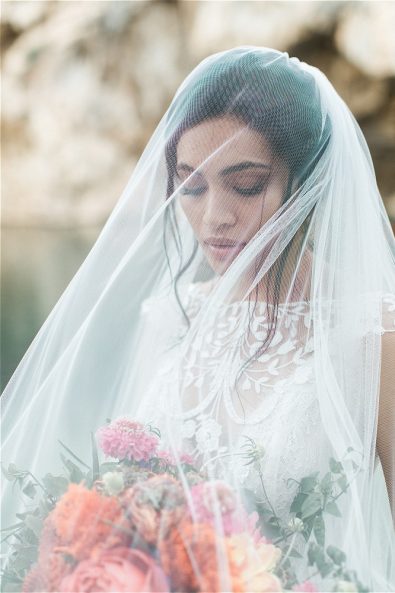 Bride wearing veil and looking at flowers