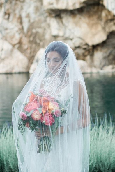 Bride wearing veil in front of Lake vouliagmeni for her elopement in Greece