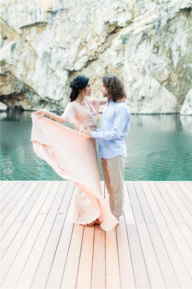 Groom holding bride in front of Lake Vouliagmeni