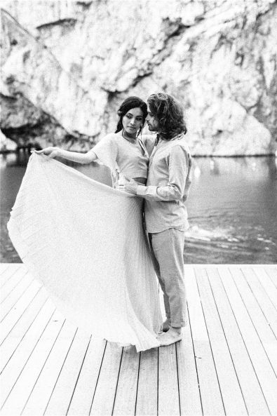 Black and White photo of Groom holding bride in front of Lake Vouliagmeni
