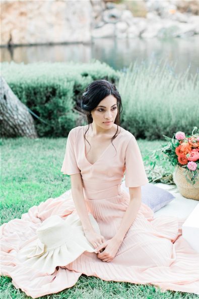 Bride sitting on picning cloth in front of Lake Vouliagmeni