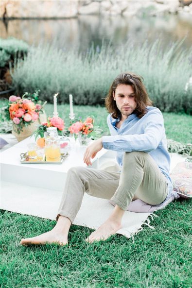 Barefoot Groom sitting on picnic cloth at his elopement in Greece