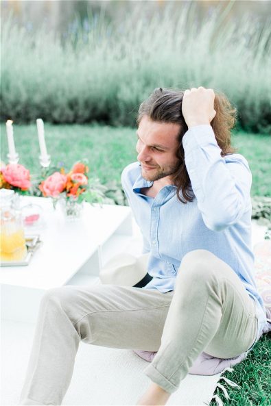 Smiling groom sitting down and fixing his hair