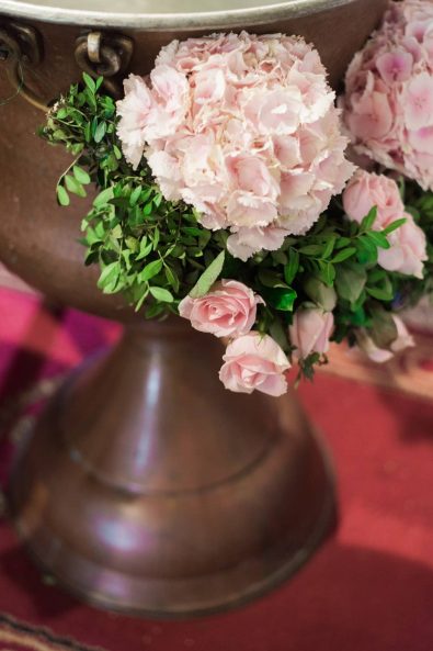 Baptistery flower decoration with pink flowers, hydrangeas, roses, and green leaves for a baby christening.