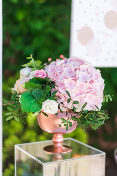 Beautiful summer flower arrangement with pink hydrangea, roses, vine leaves, and greenery.
