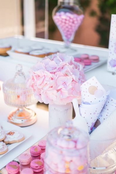 Close up shot of pink hydrangea flowers in a white vase and rose gold macarons for a candy bar.