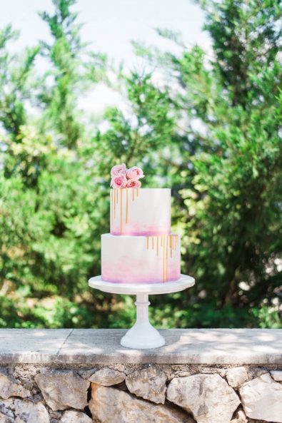 Pastel colored double tier cake with gold drip for a baptism in Greece.