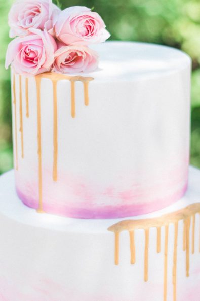 baby christening - Close up shot of pastel-colored cake with pink ombre effect and gold drip.