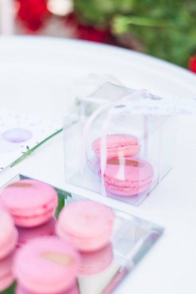 Close up shot of vibrant pink and gold macarons baptism christening favors Bomboniere in a plexiglass transparent box.