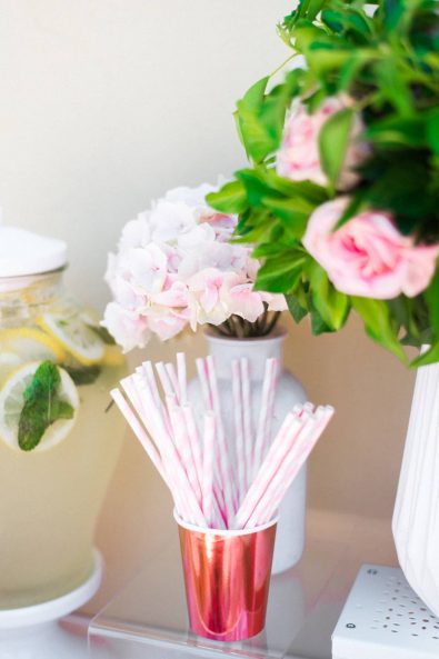 Copper colored paper party cup filled with stripy pink and white straws.