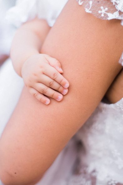 Close up shot of baby's tiny hand clasping his mother's arm at a baby christening.