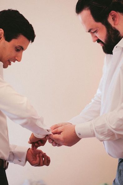 The groom and his best man doing his cufflinks.