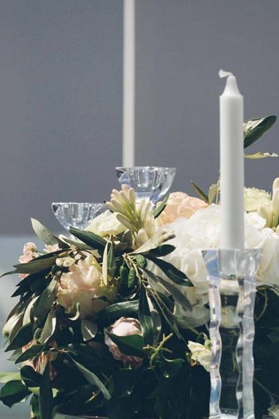Flower arrangement with hydrangeas and roses on a glass table and crystal candle holders.