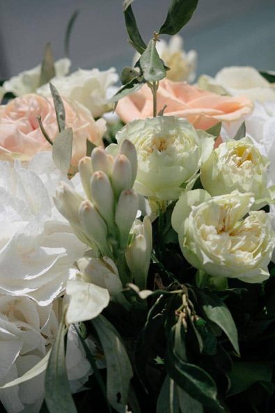 Wedding flower arrangement with hydrangeas, peach and white roses, white blooms and greenery.